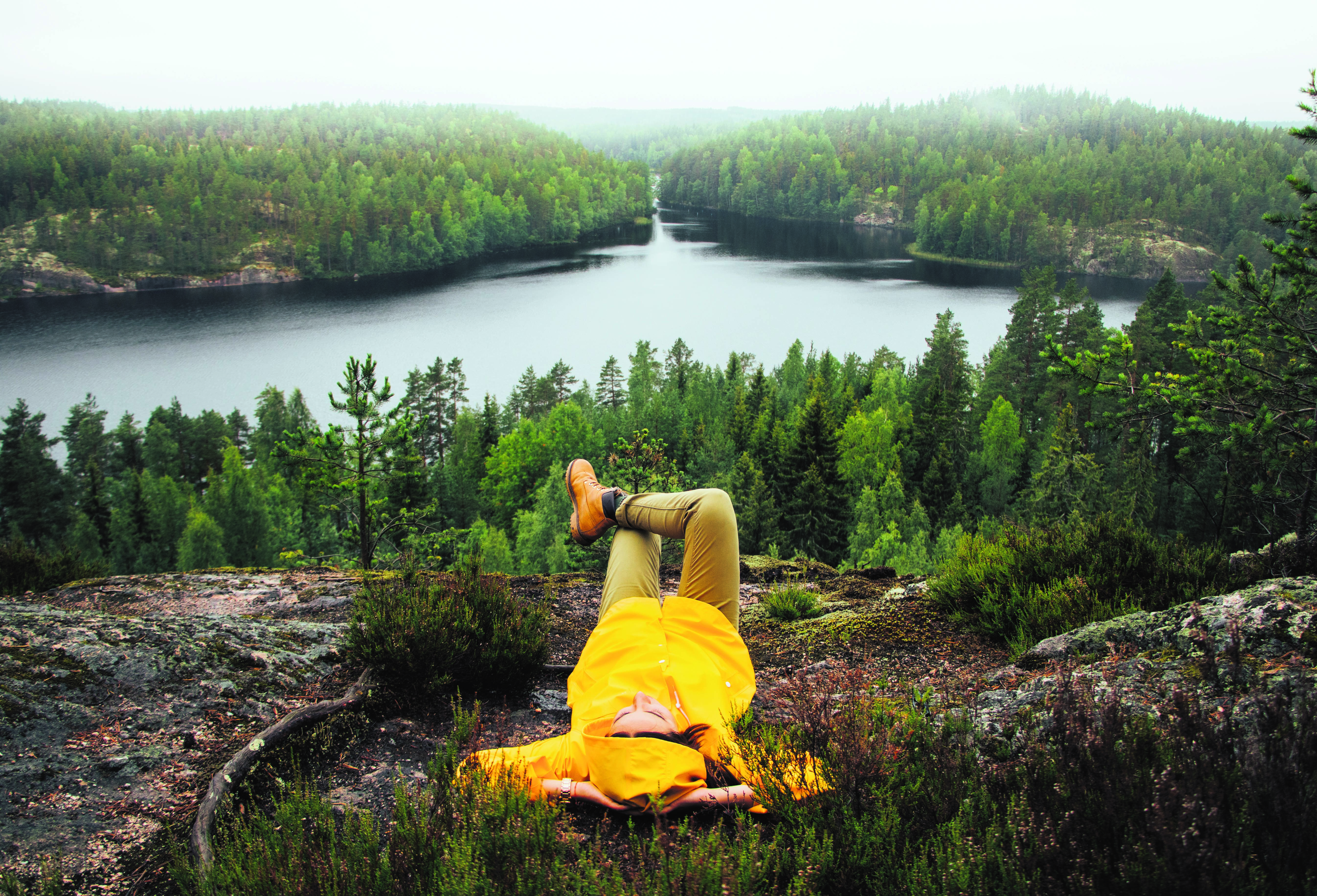 A person is lying down in front of a Lake landscape in Finland