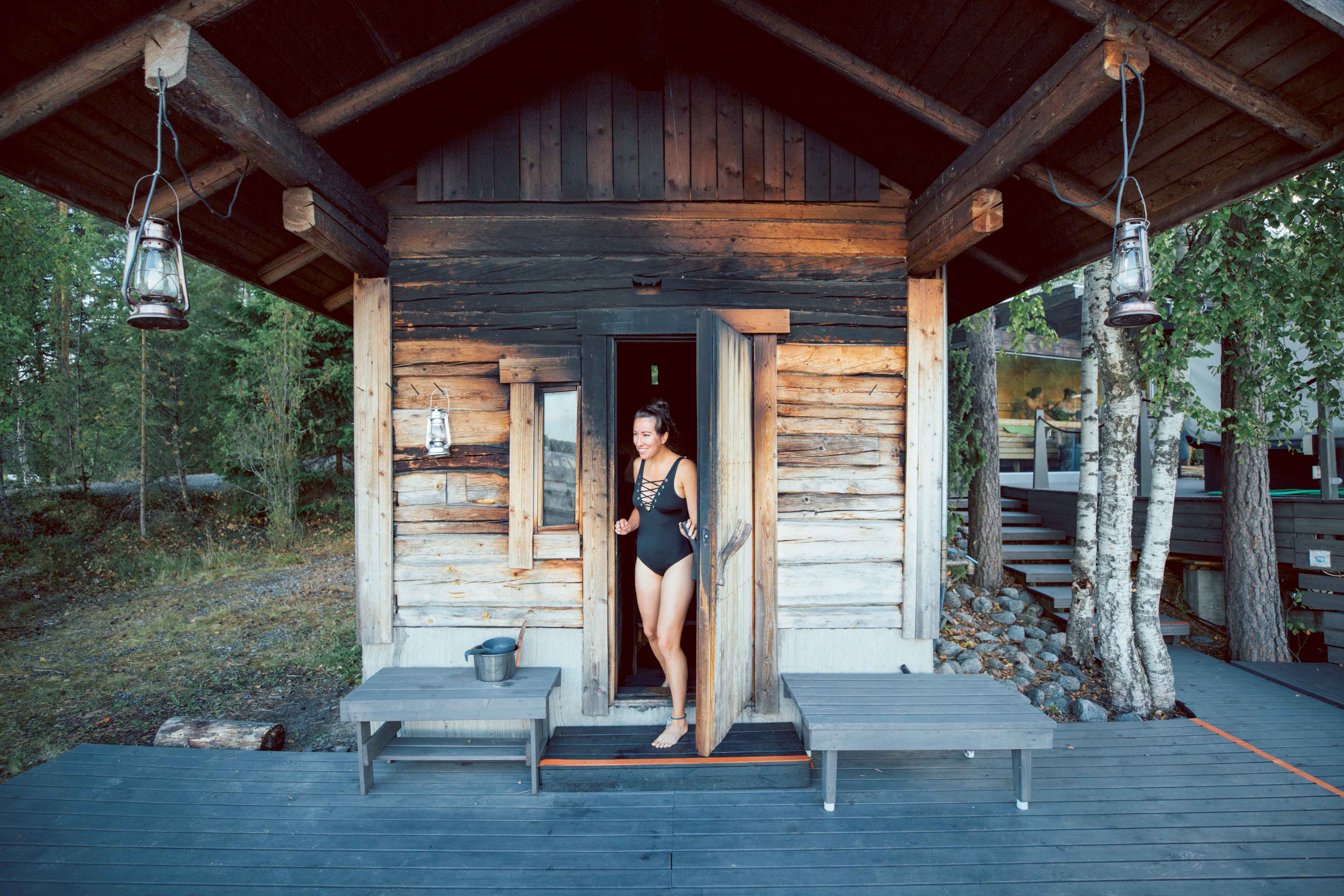 A smiling woman stepping out of a smoke sauna