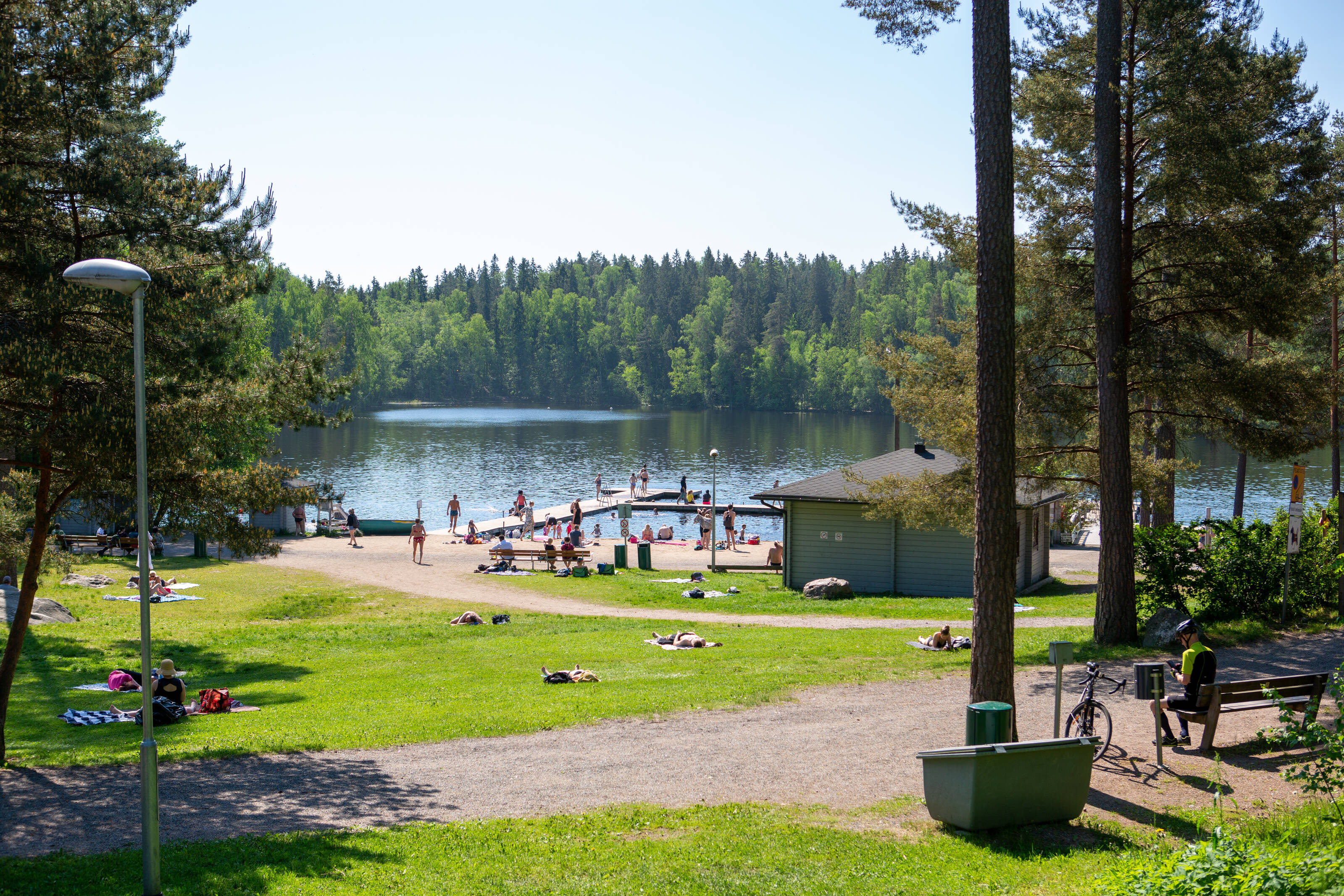 gente bañándose en un idílico lago rodeado de parque y bosque