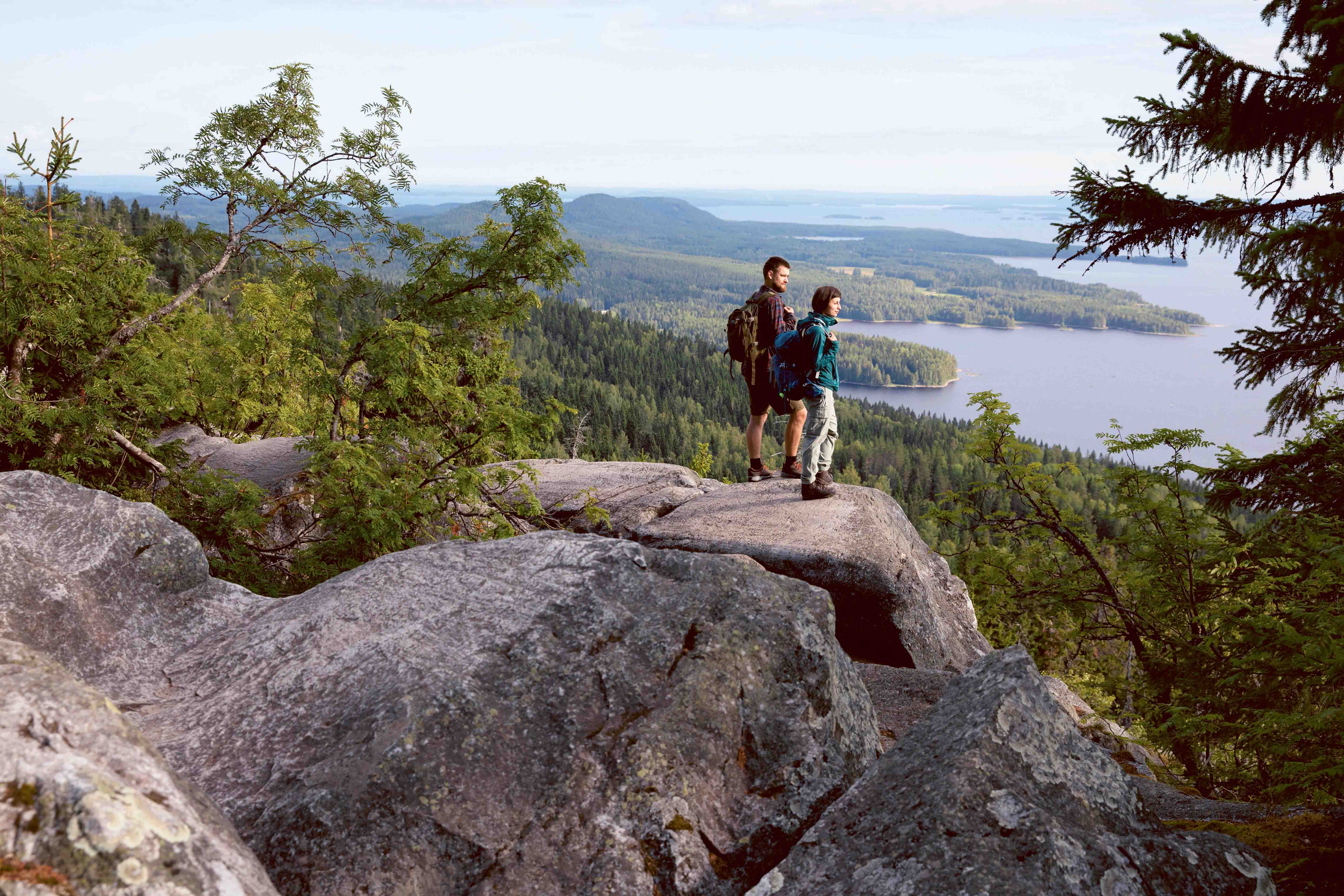 Deux personnes debout sur un rocher regardant le paysage national finlandais