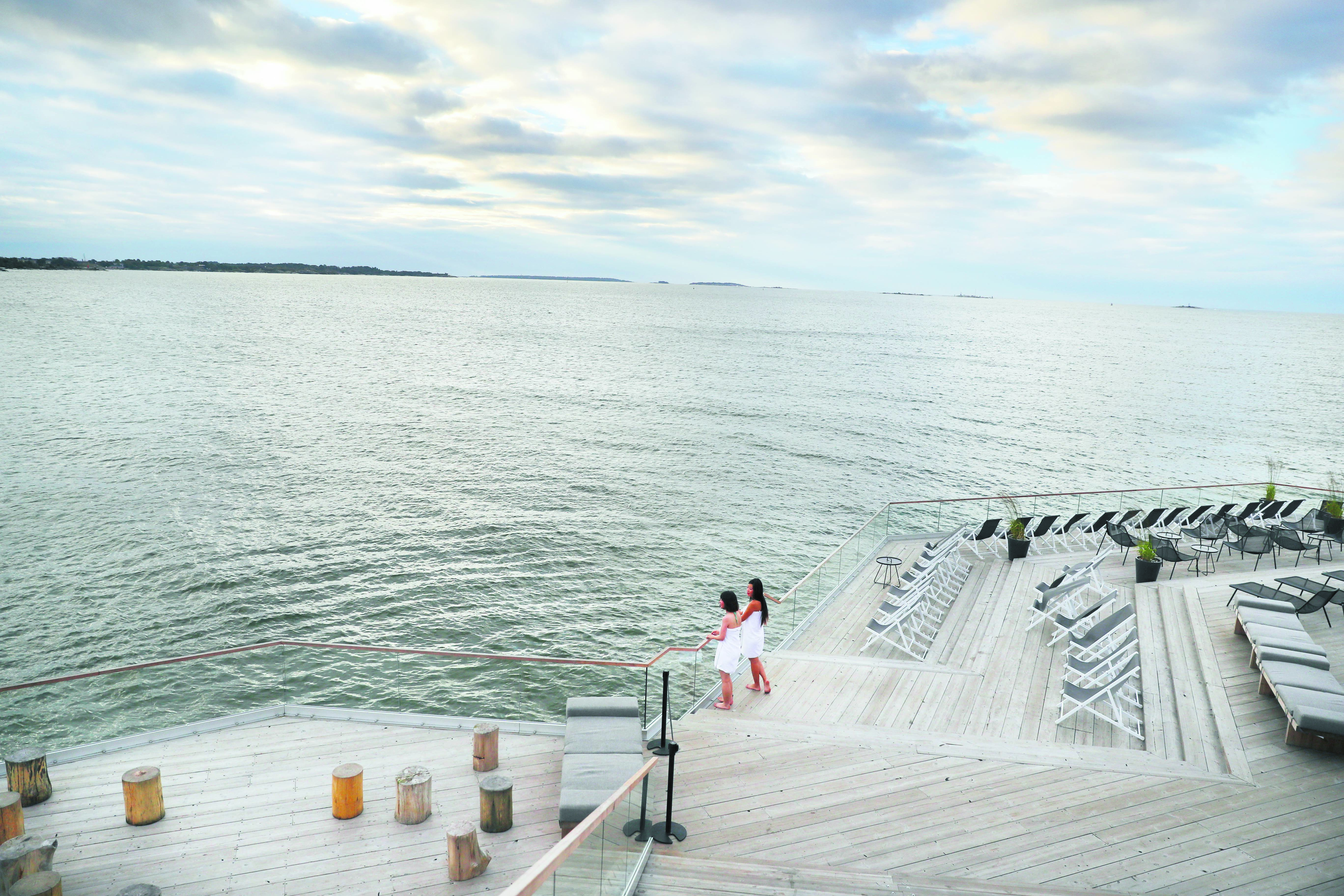 two women look out to sea from a design sauna terrace