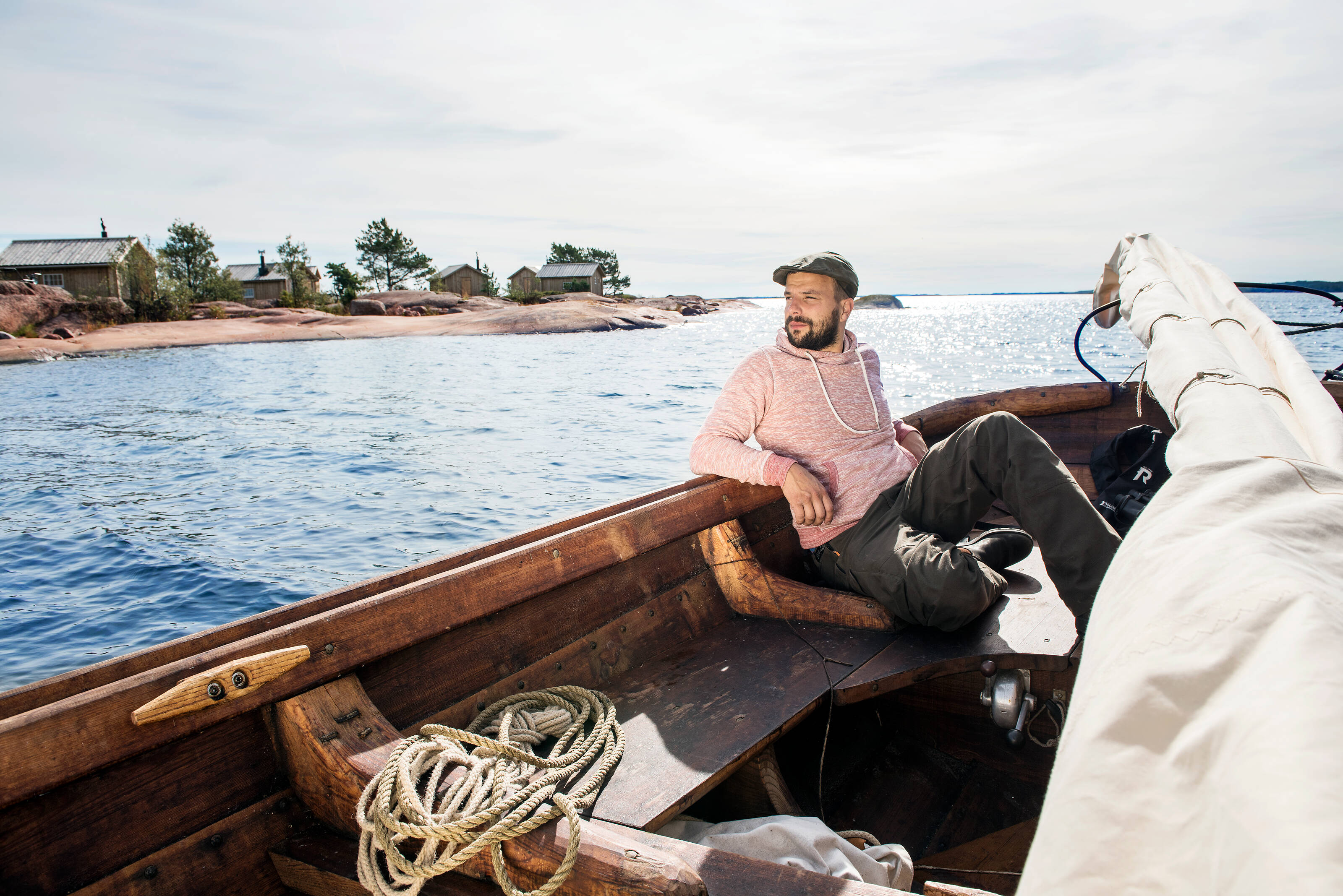 человек отдыхает в деревянной лодке среди островов Аландского архипелага