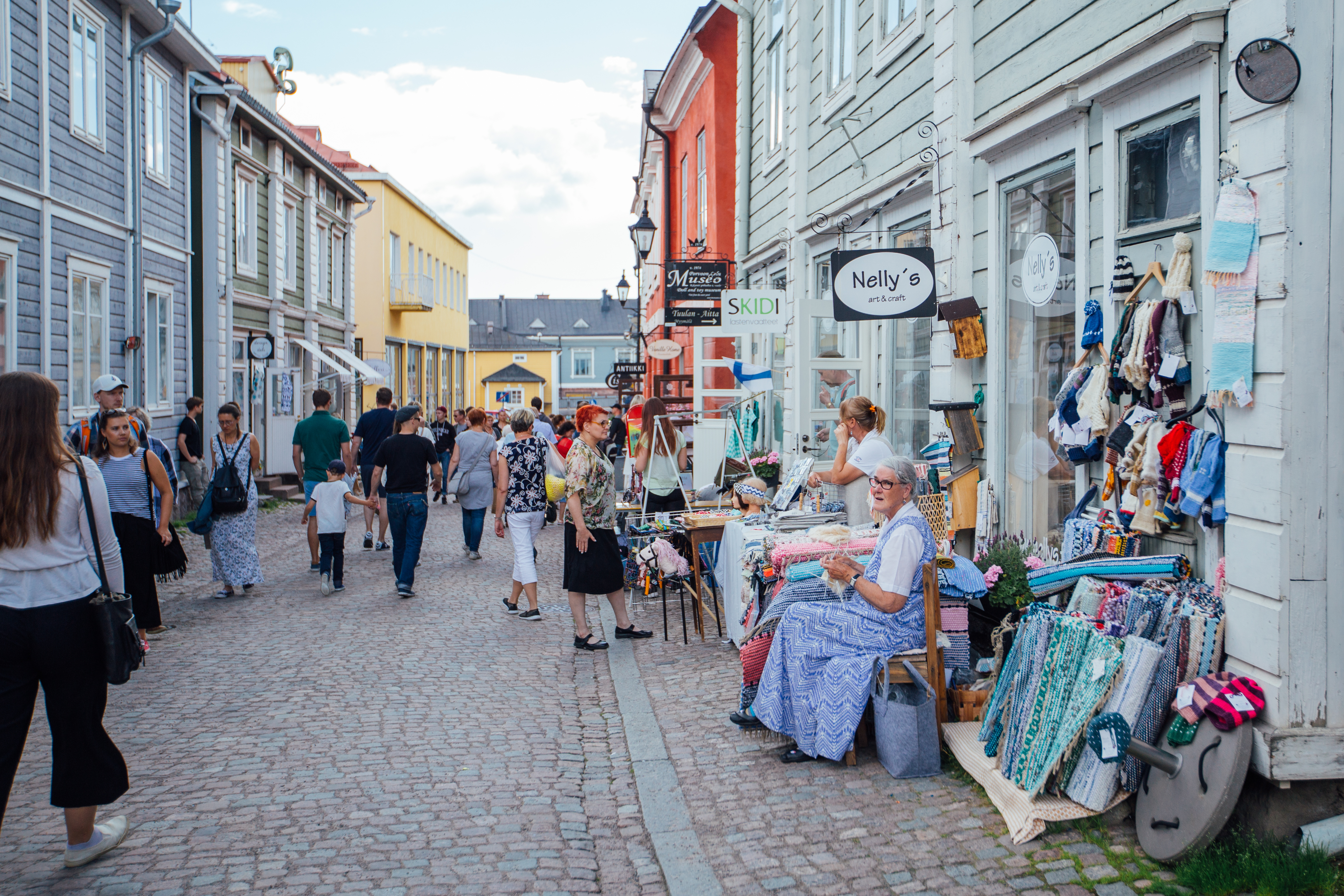 A street view of a cozy old wooden town full of people and shops
