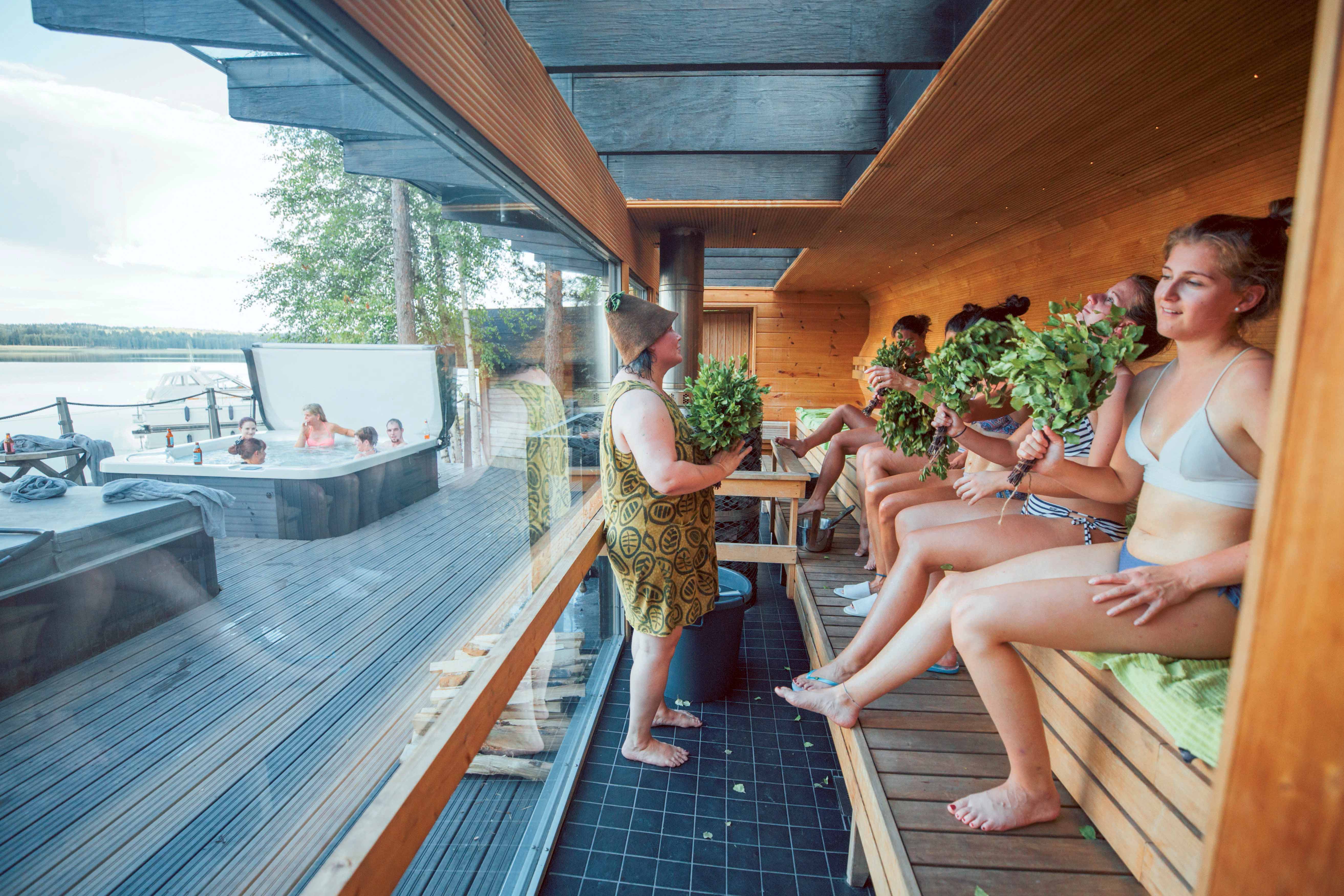 Una sauna piena di persone che si divertono con ramoscelli di betulla