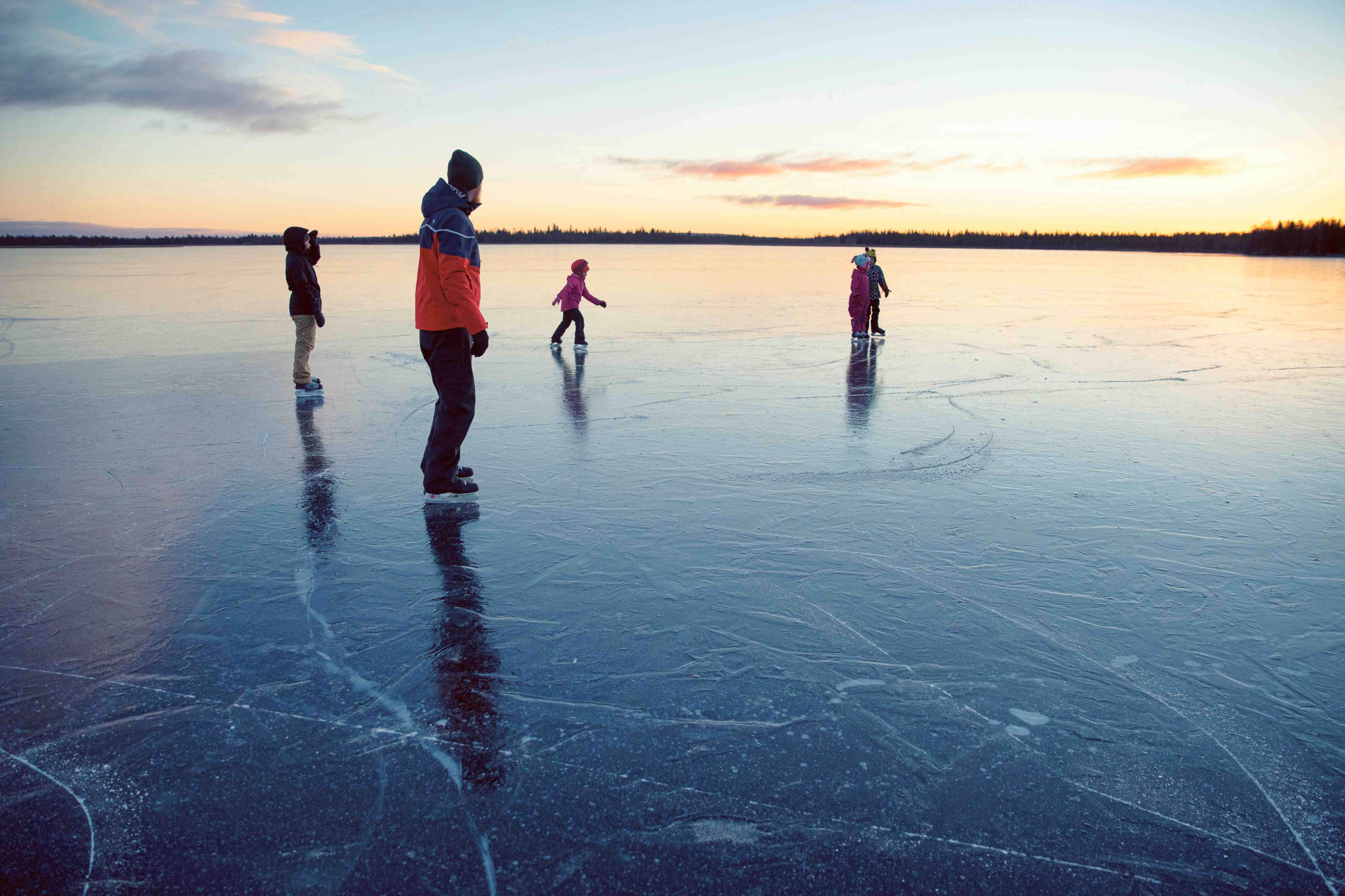 Семья катается на коньках по замерзшему озеру в Озерном краю Финляндии