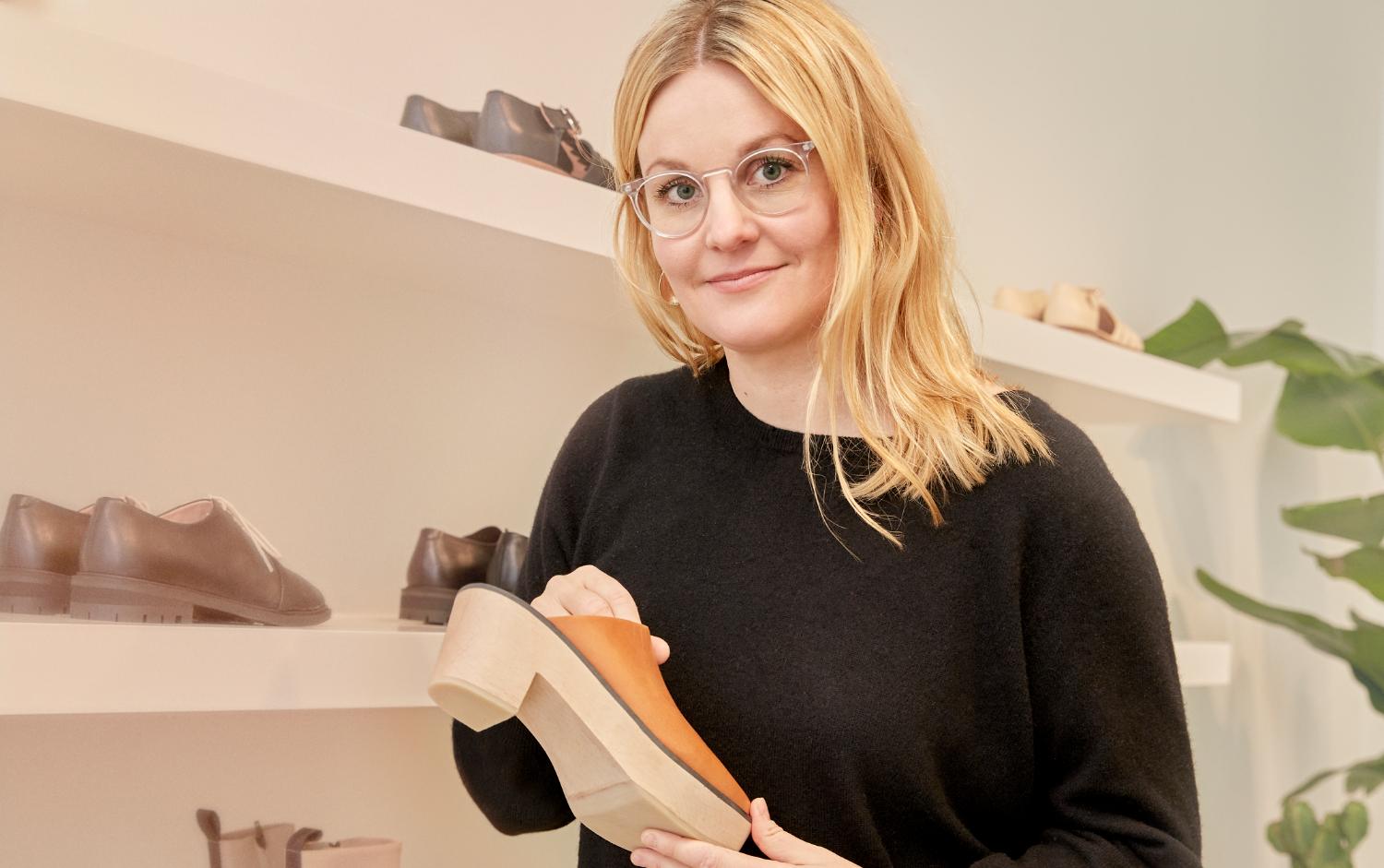 La créatrice tenant en main une chaussure à la boutique phare d’Helsinki