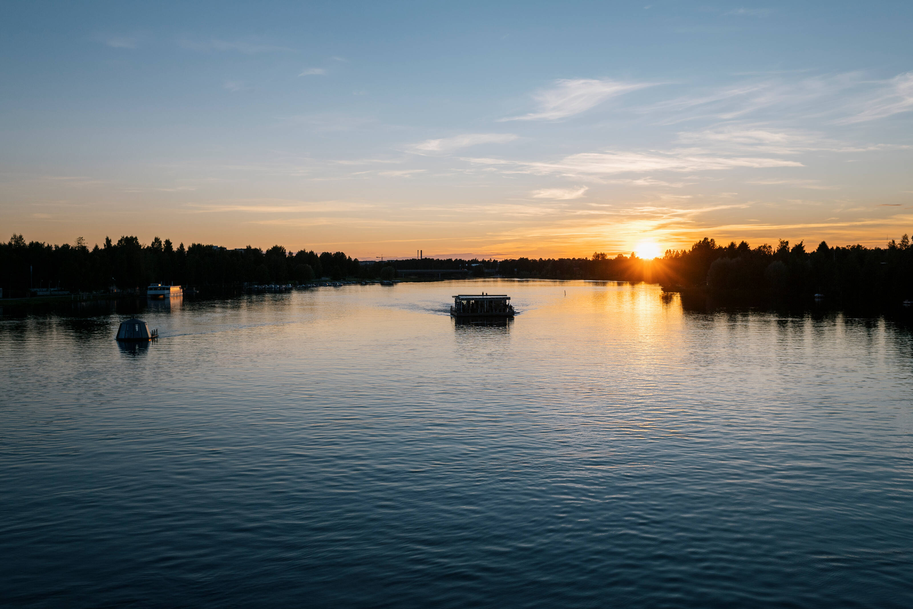 Ein Saunafloss gleitet über einen finnischen Fluss in Richtung Sonnenuntergang