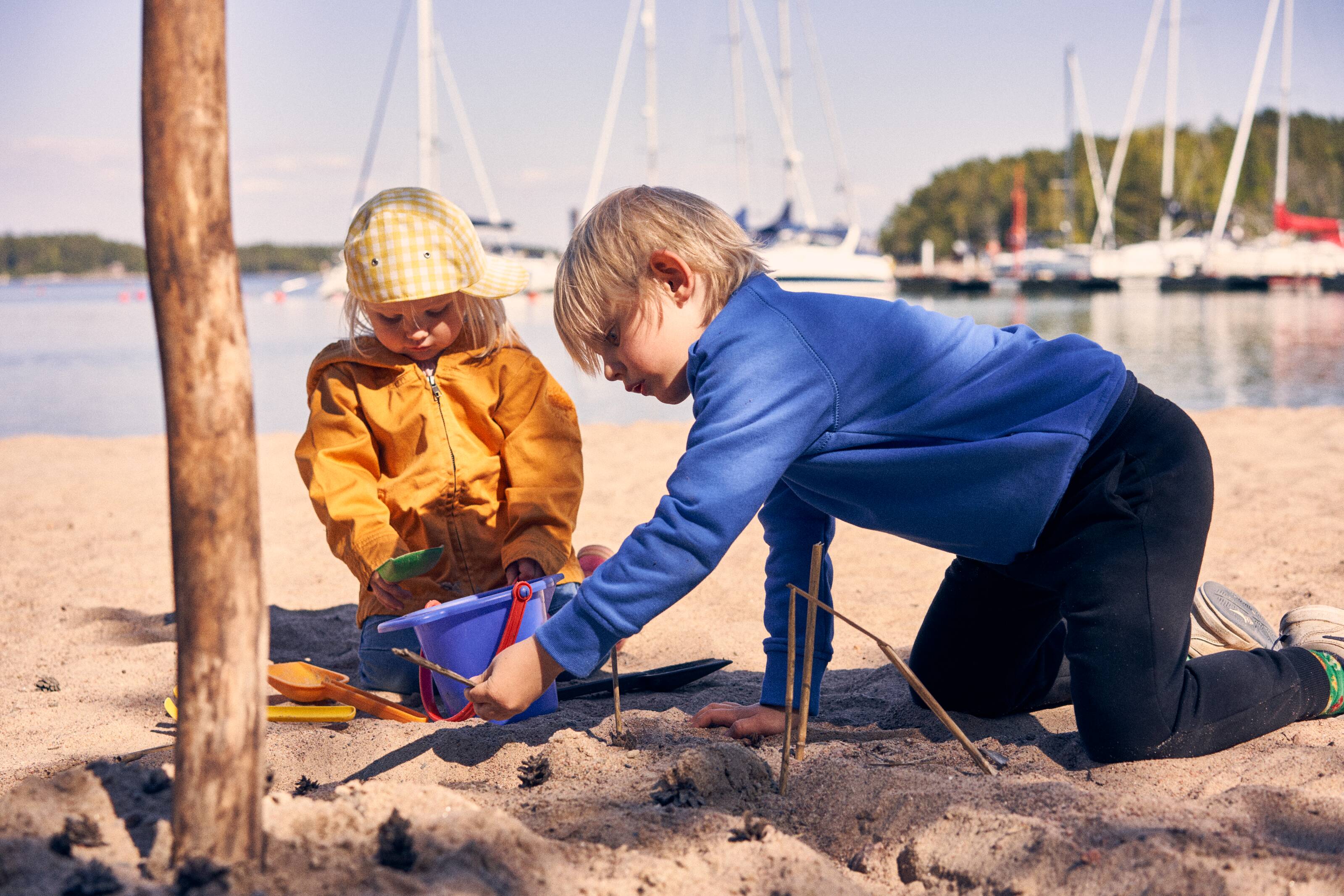 Zwei Kinder spielen an einem Strand in den finnischen Schären
