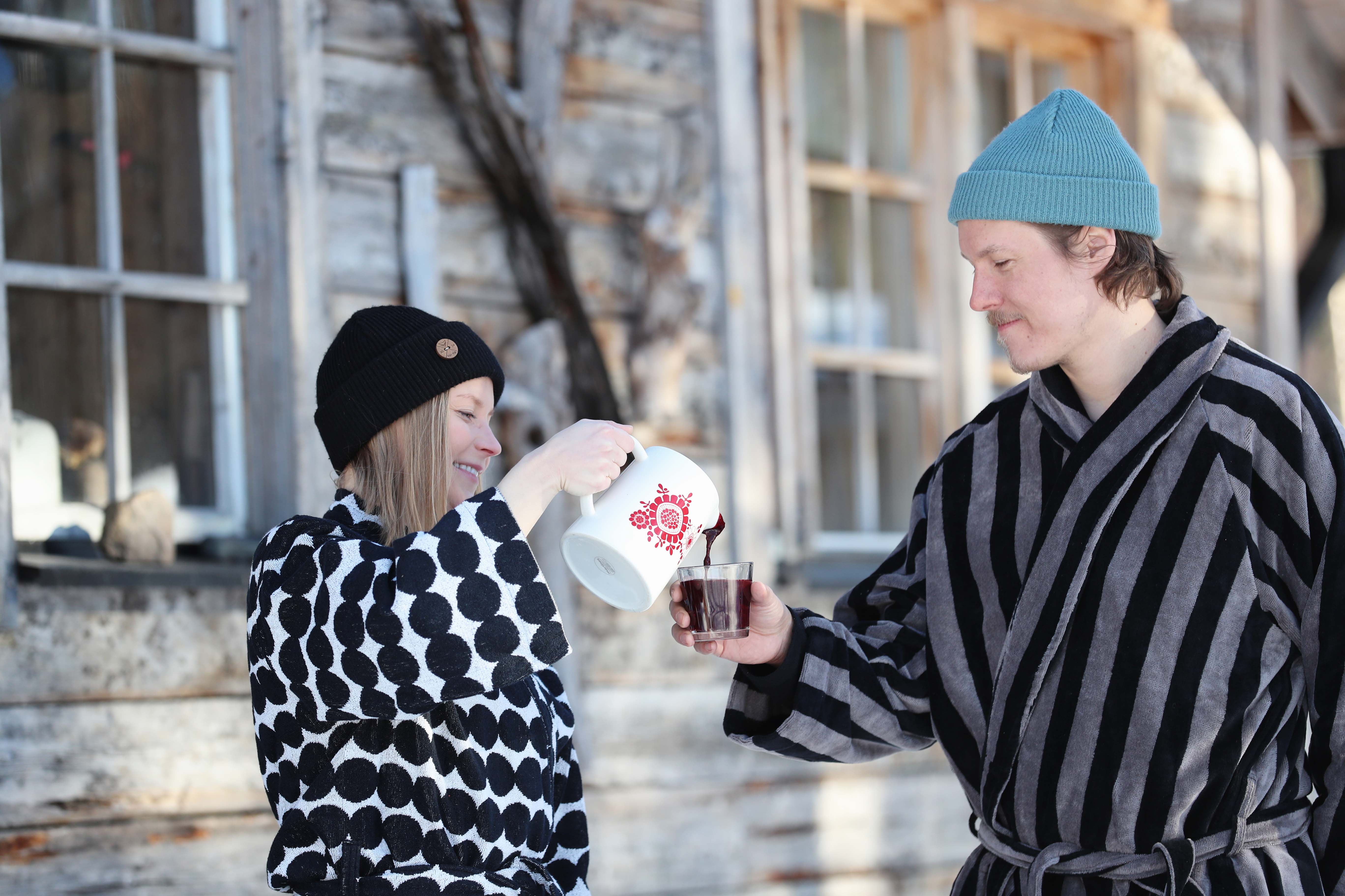 A couple enjoying hot beverages outside in a snow after sauna bathing