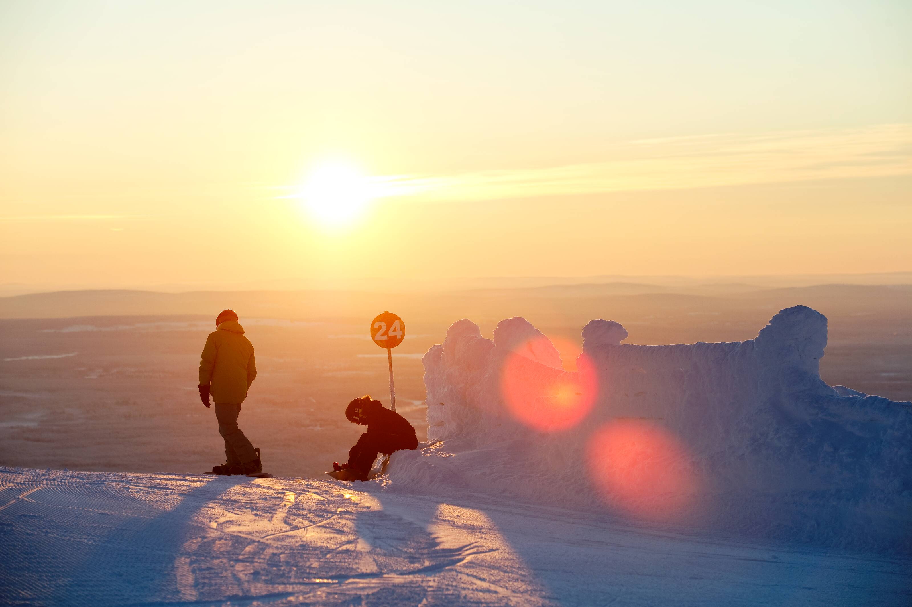 two snowboarders prepare to descend a slope in a Finnish fell landscape
