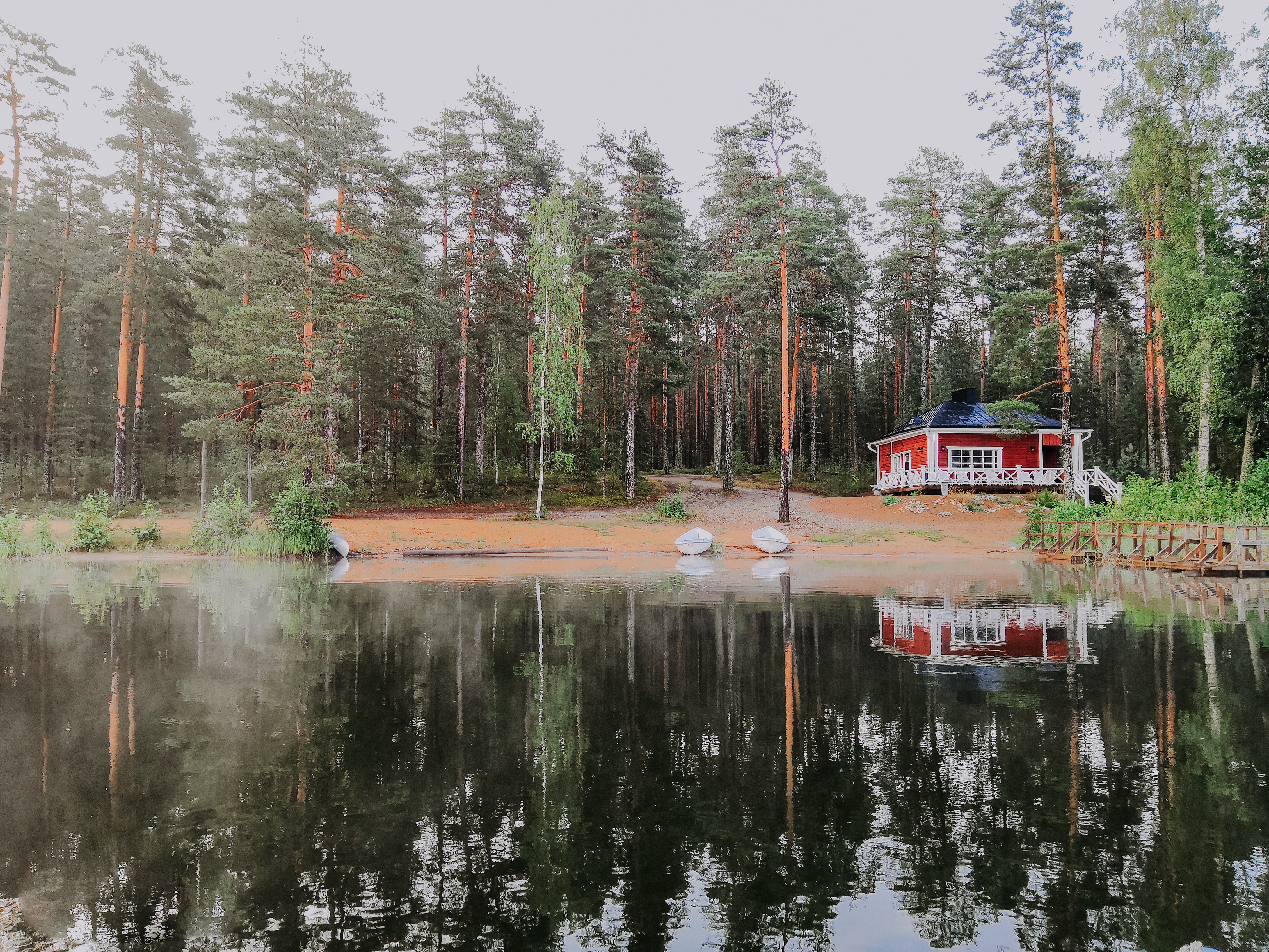 un idílico edificio rojo de madera junto al lago en medio de un bosque