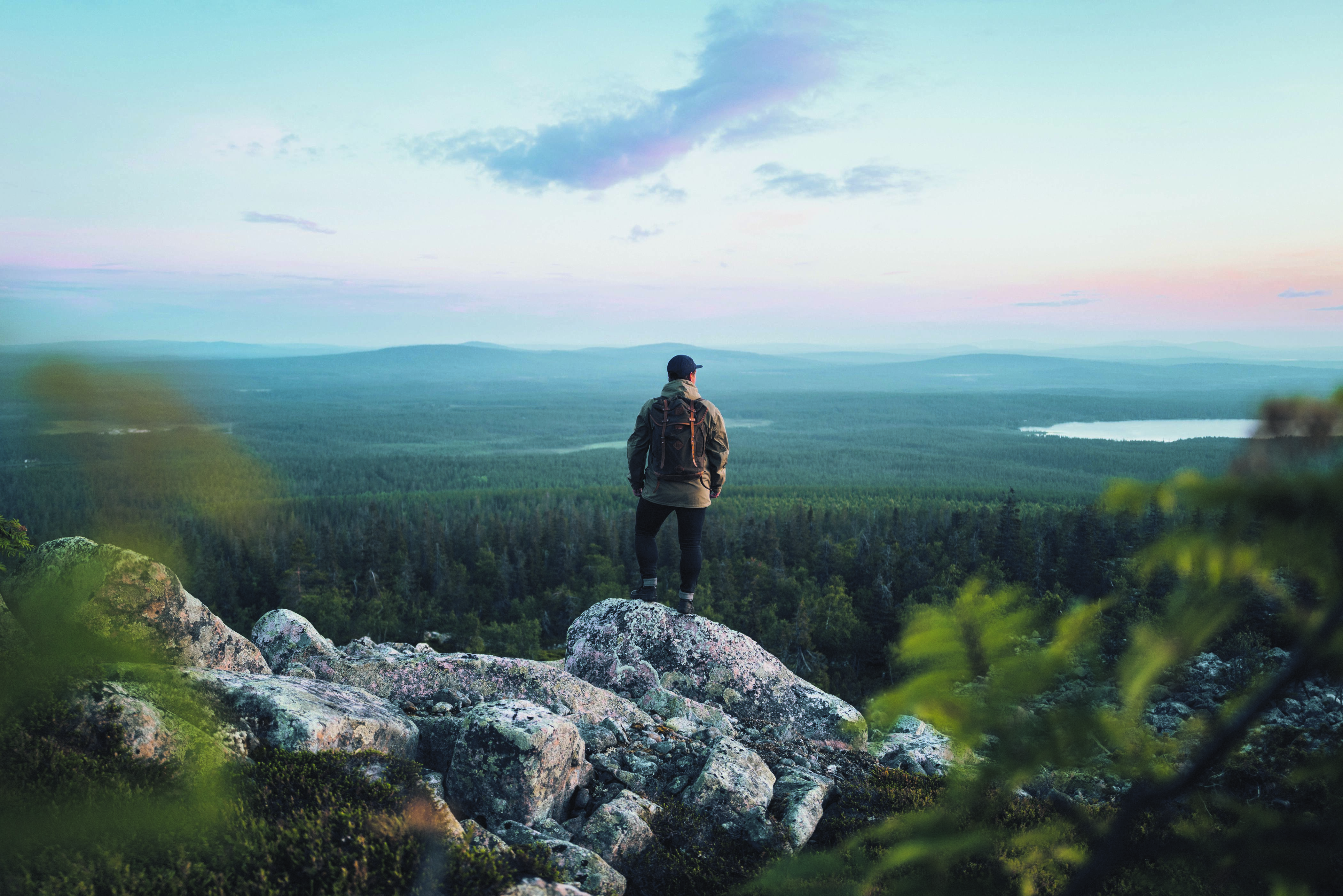 Wanderer auf einem Berg, der auf eine finnische Waldlandschaft blickt