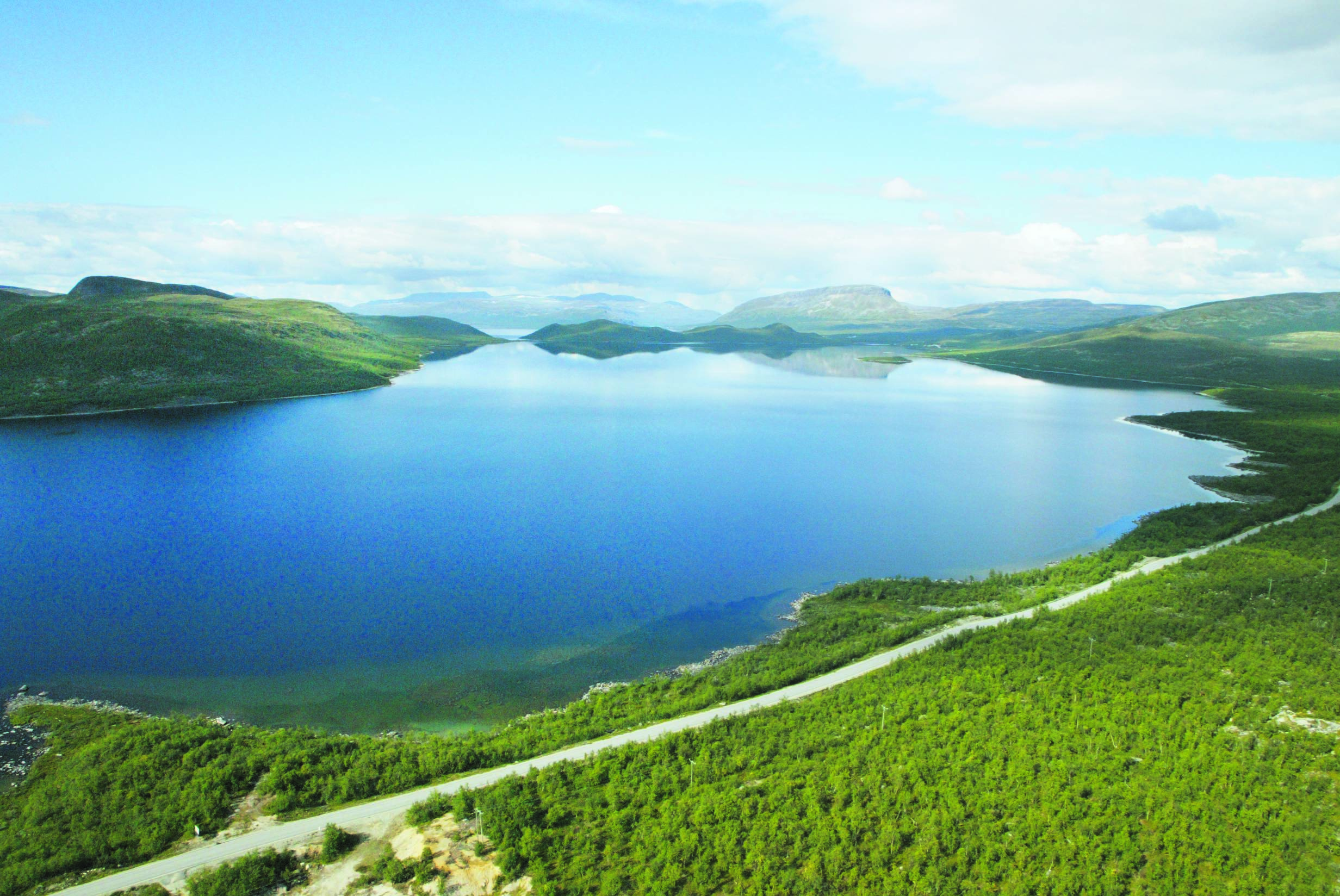 Landschaftsaufnahme mit einem blauen See sowie Fjells und Bergen am Horizont