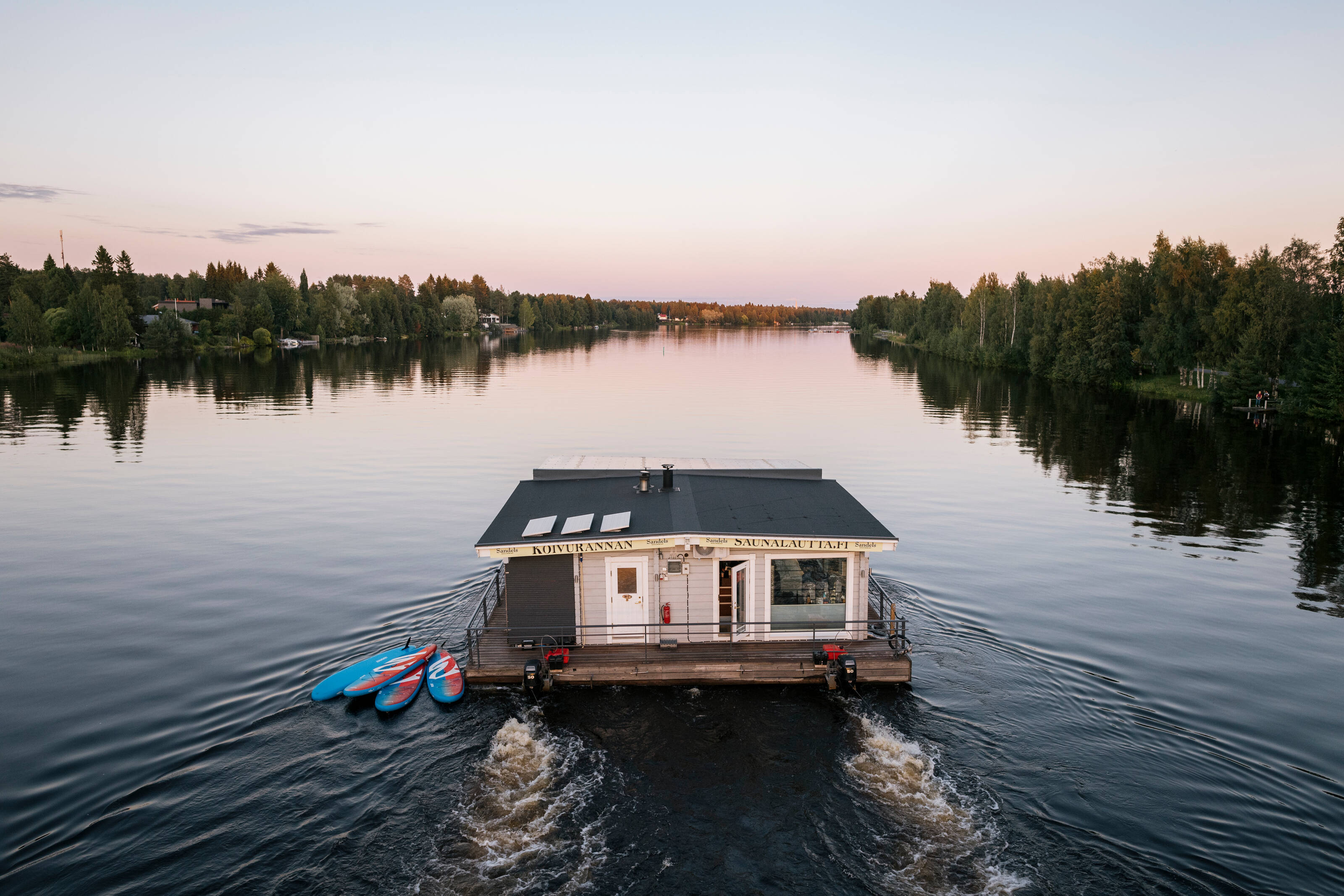 a close up of a floating sauna raft by the river heading to the sunset
