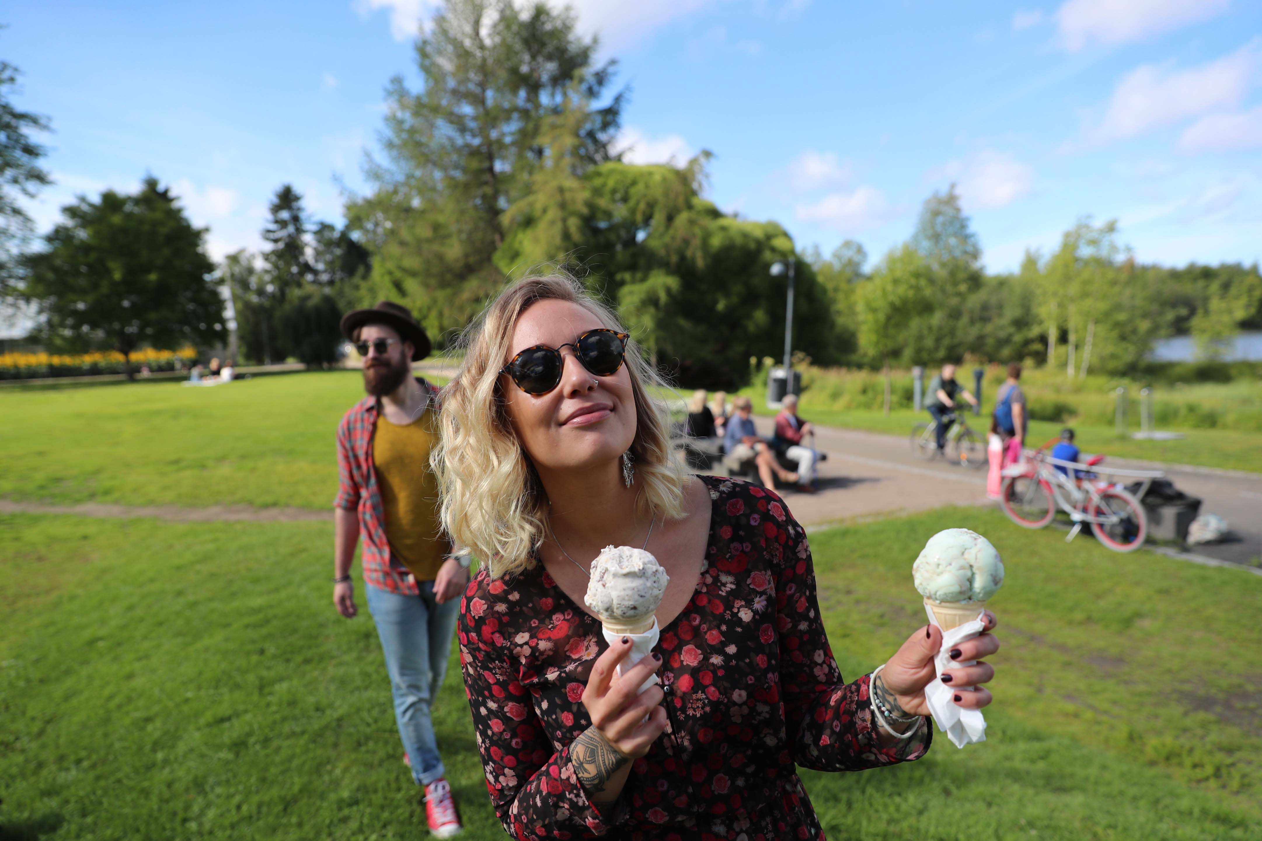 una donna con in mano due gelati mentre cammina in un parco di Oulu, in Finlandia