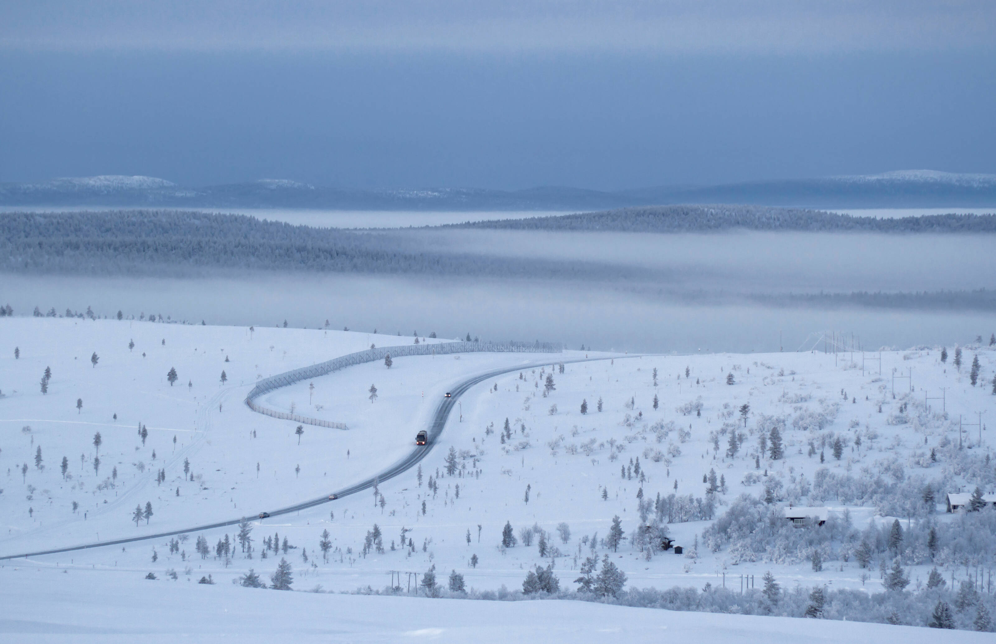 a landscape picture of a snowy Lapland where a road crosses the landscape