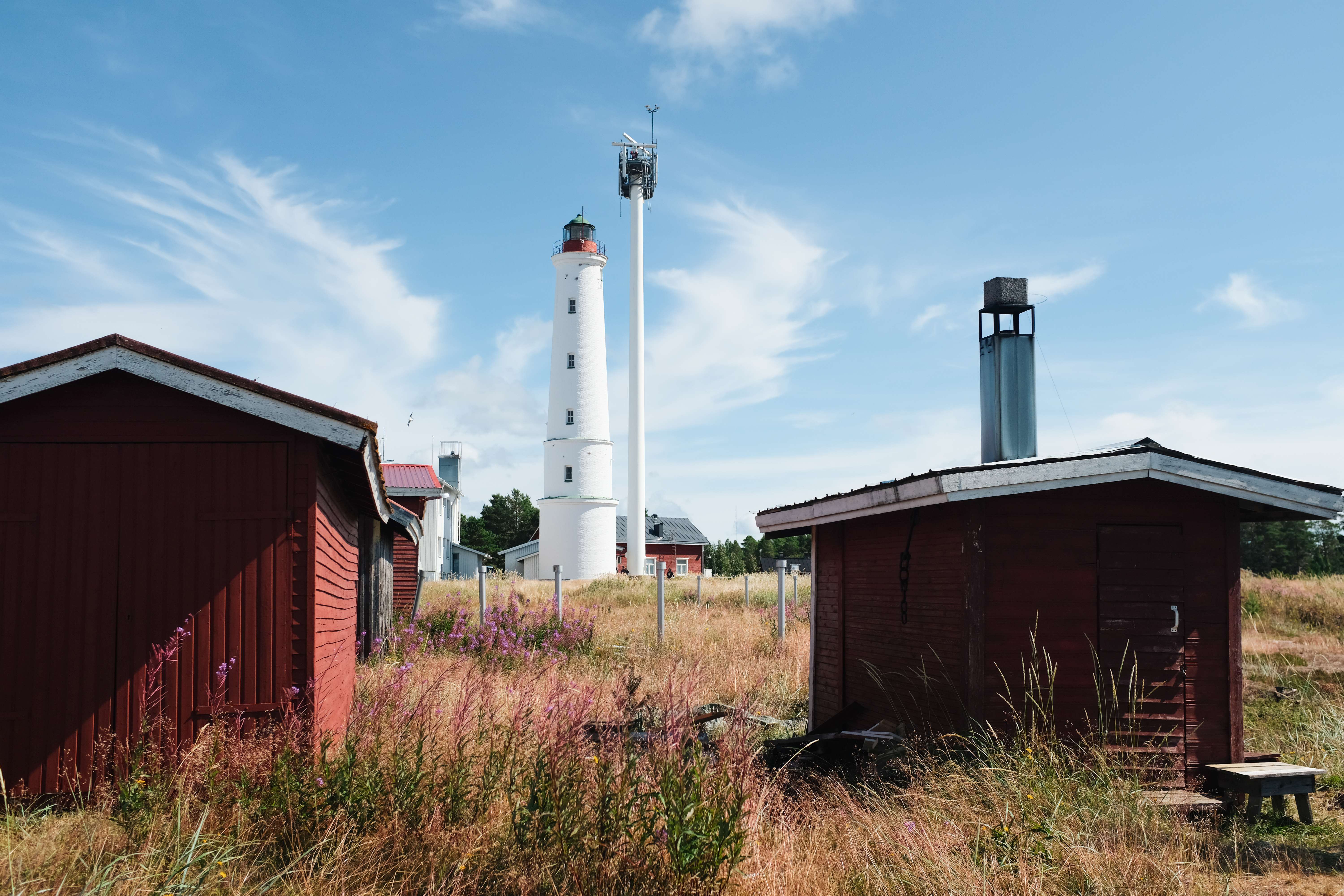 Der weiße Leuchtturm auf Hailuoto in Finnland umgeben von roten Holzhäusern