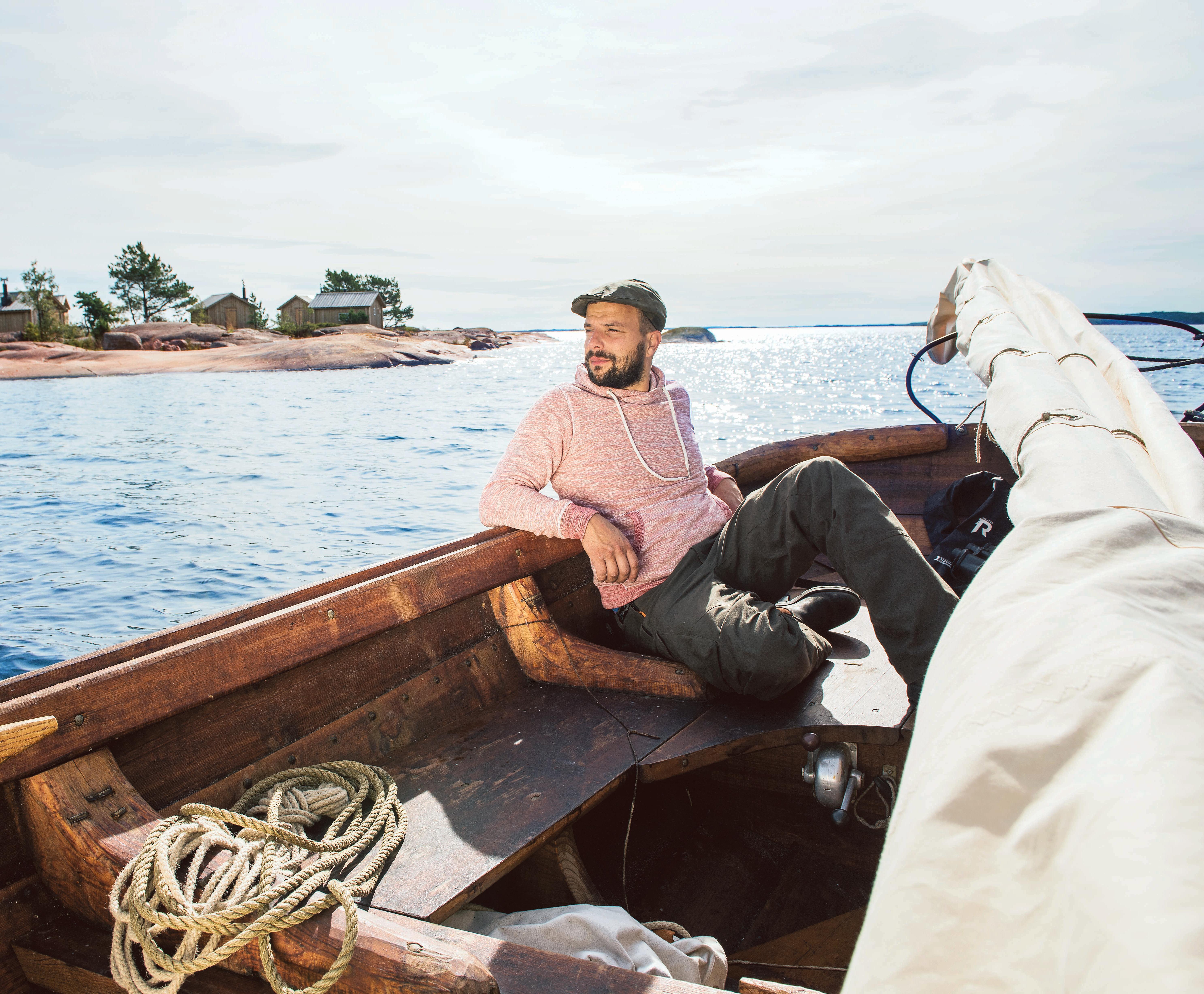 A man sailing in a traditional wooden boat in the Åland archipelago