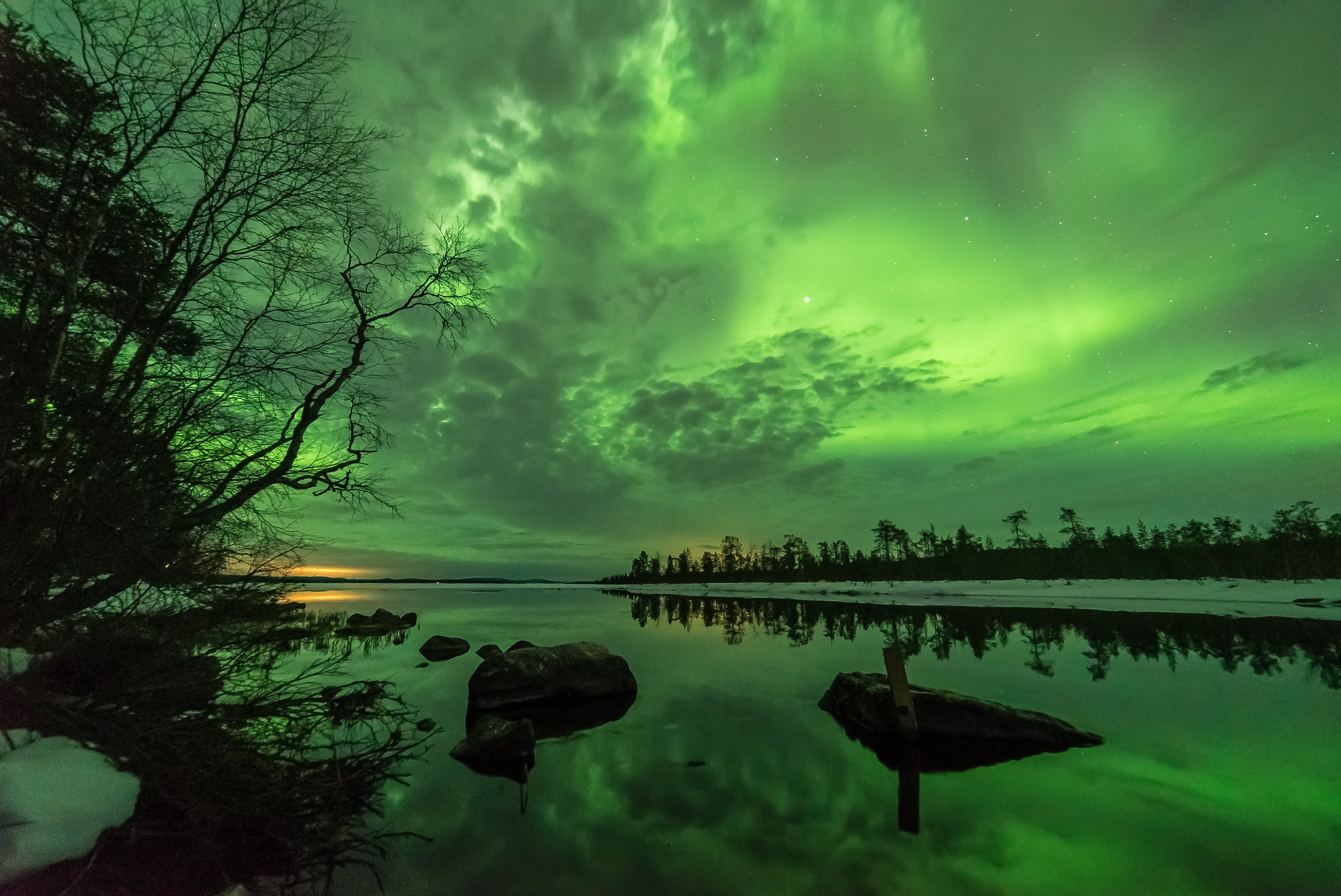 Green northern lights above a lake