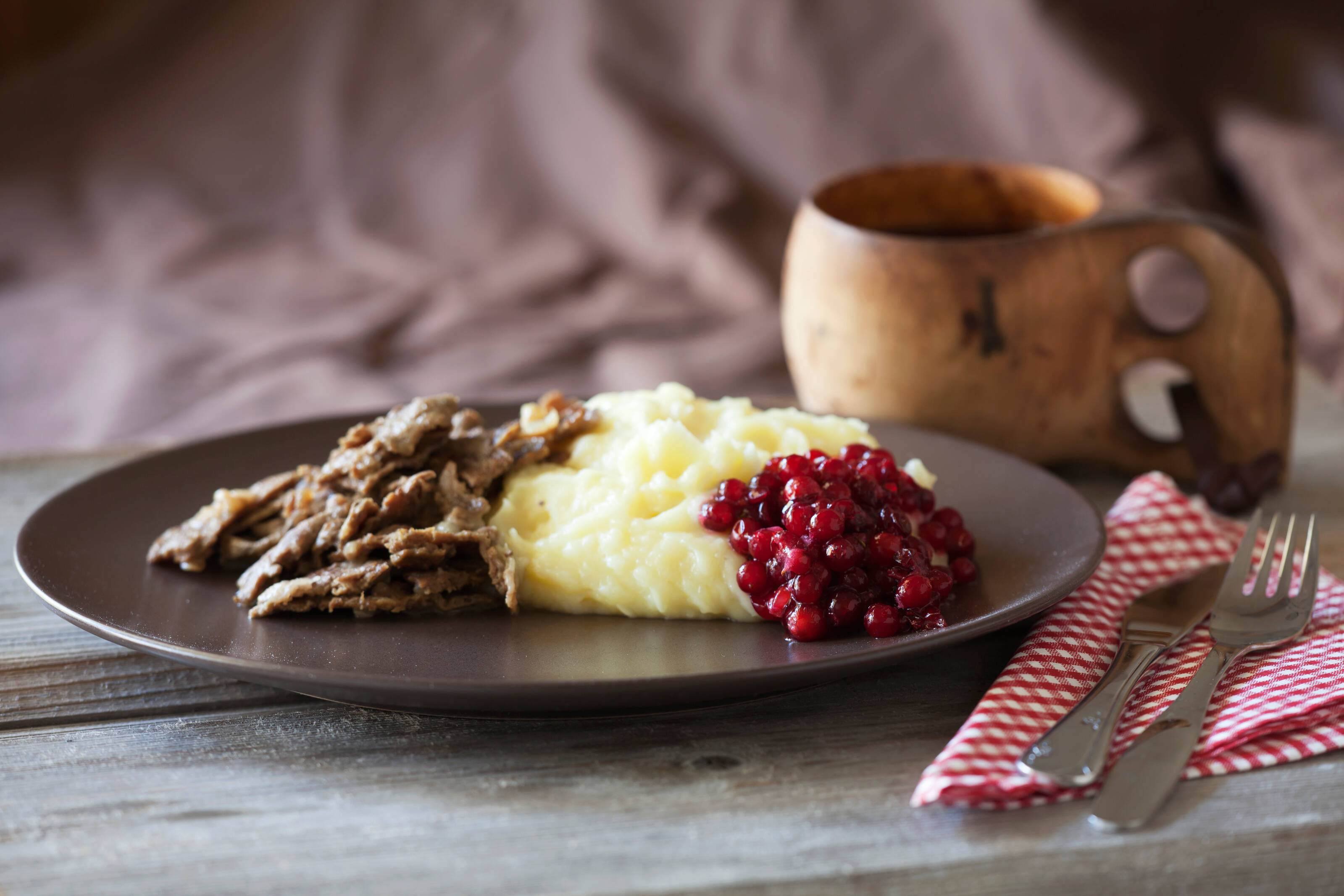 Un plat traditionnel finlandais contenant du renne sauté, de la purée de pommes de terre et des airelles