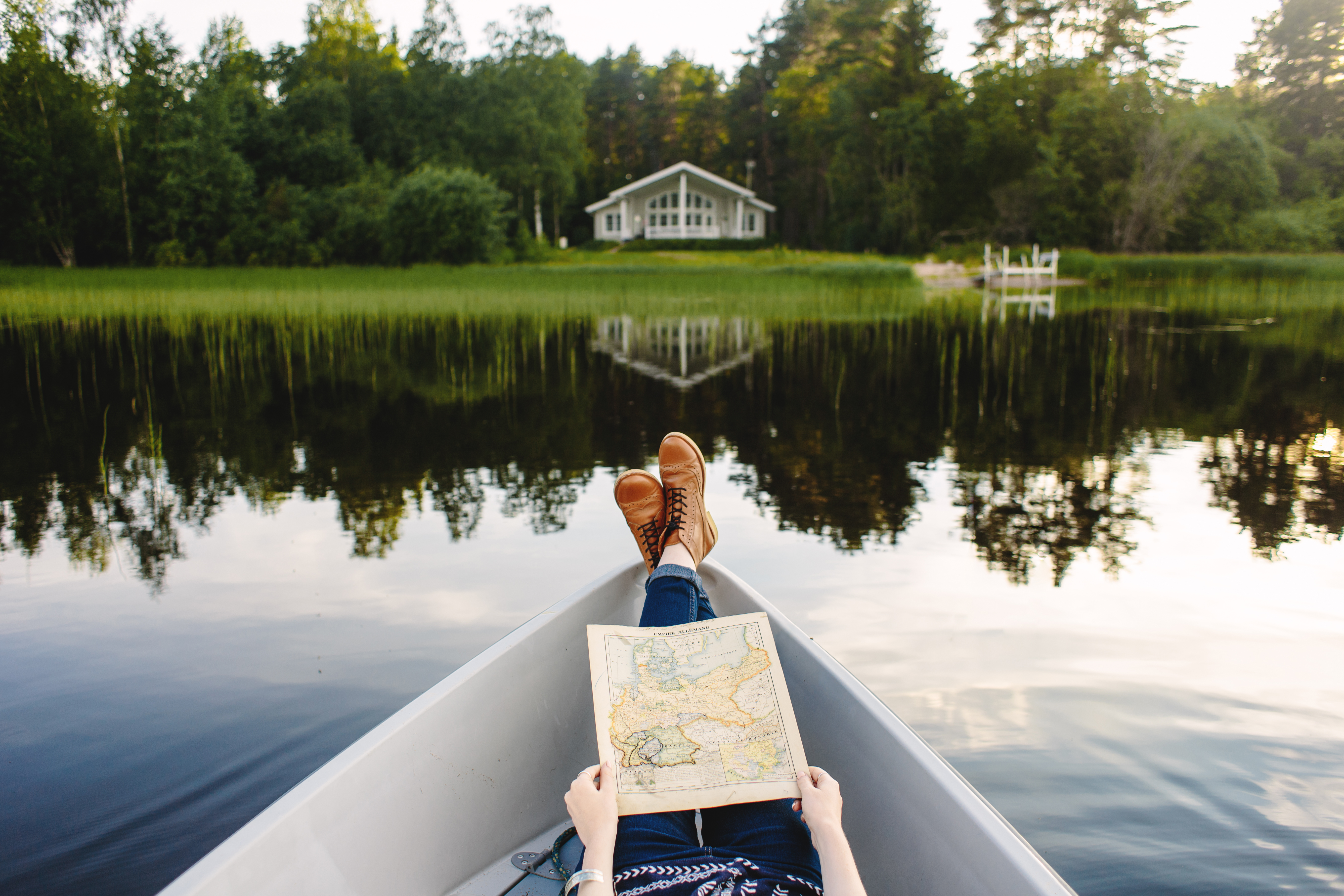 A person is lying down in a boat in front of a Lake landscape in Finland