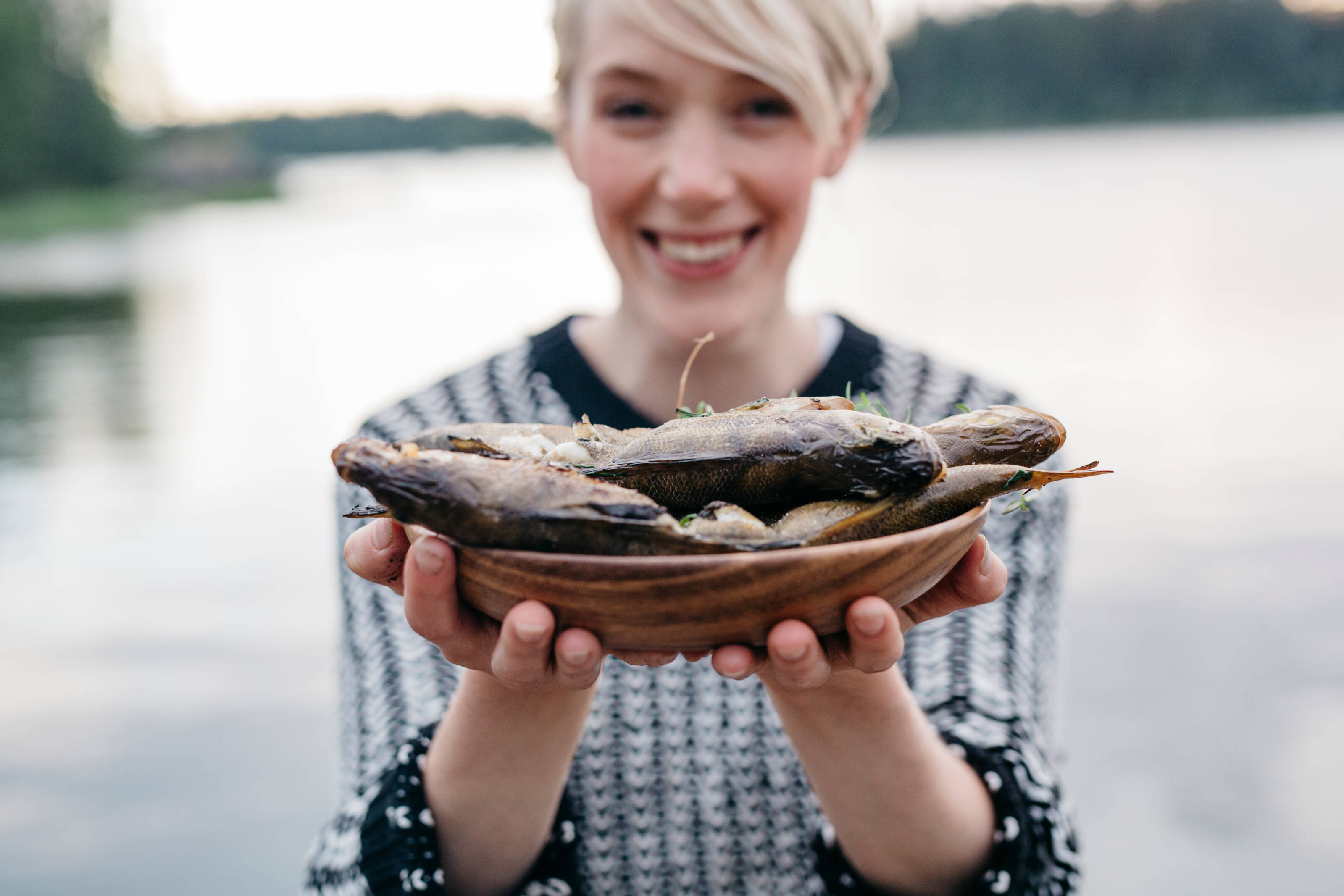 Женщина держит тарелку с копченой рыбой