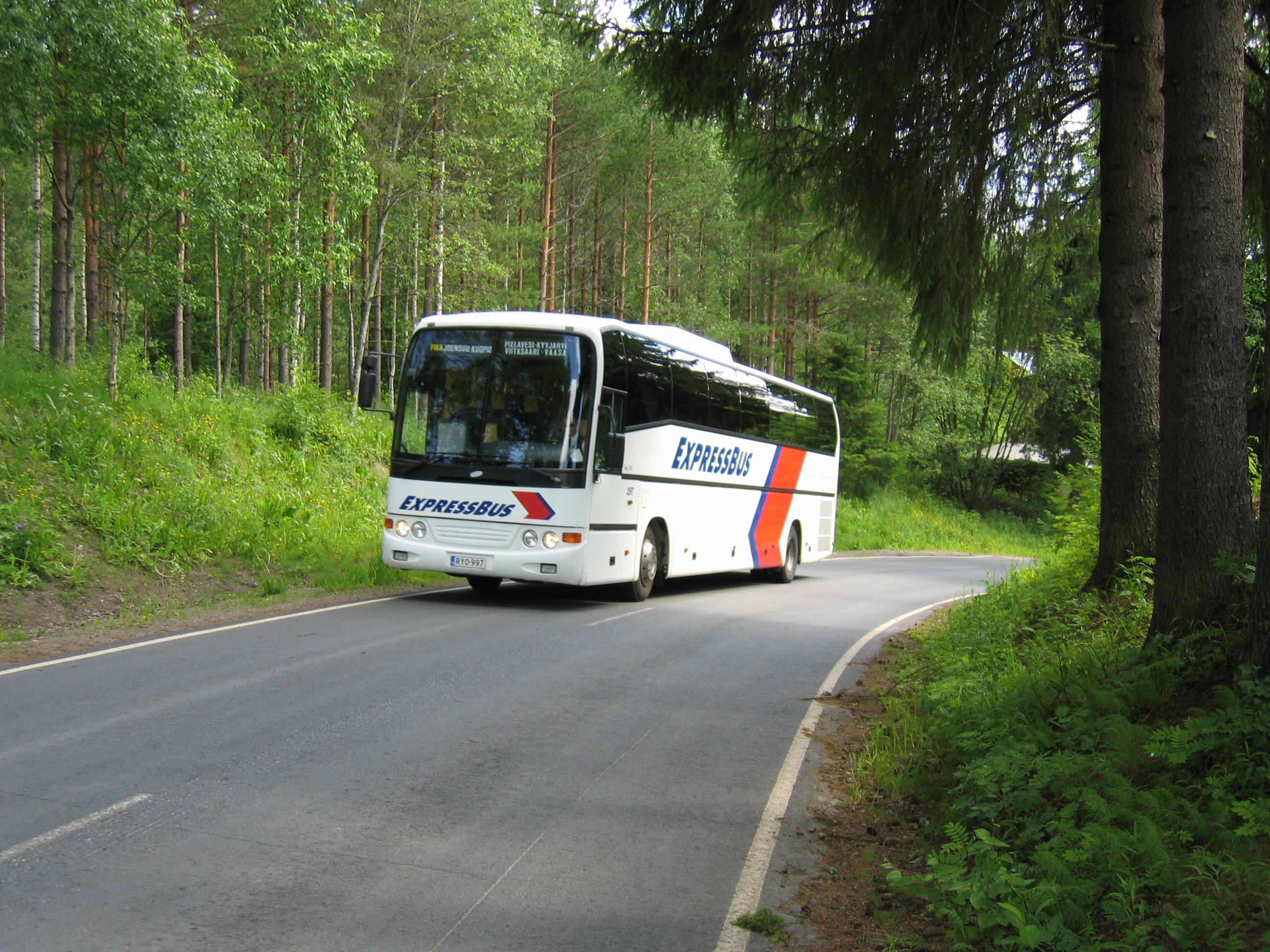 A bus driving through a Finnish forest.
