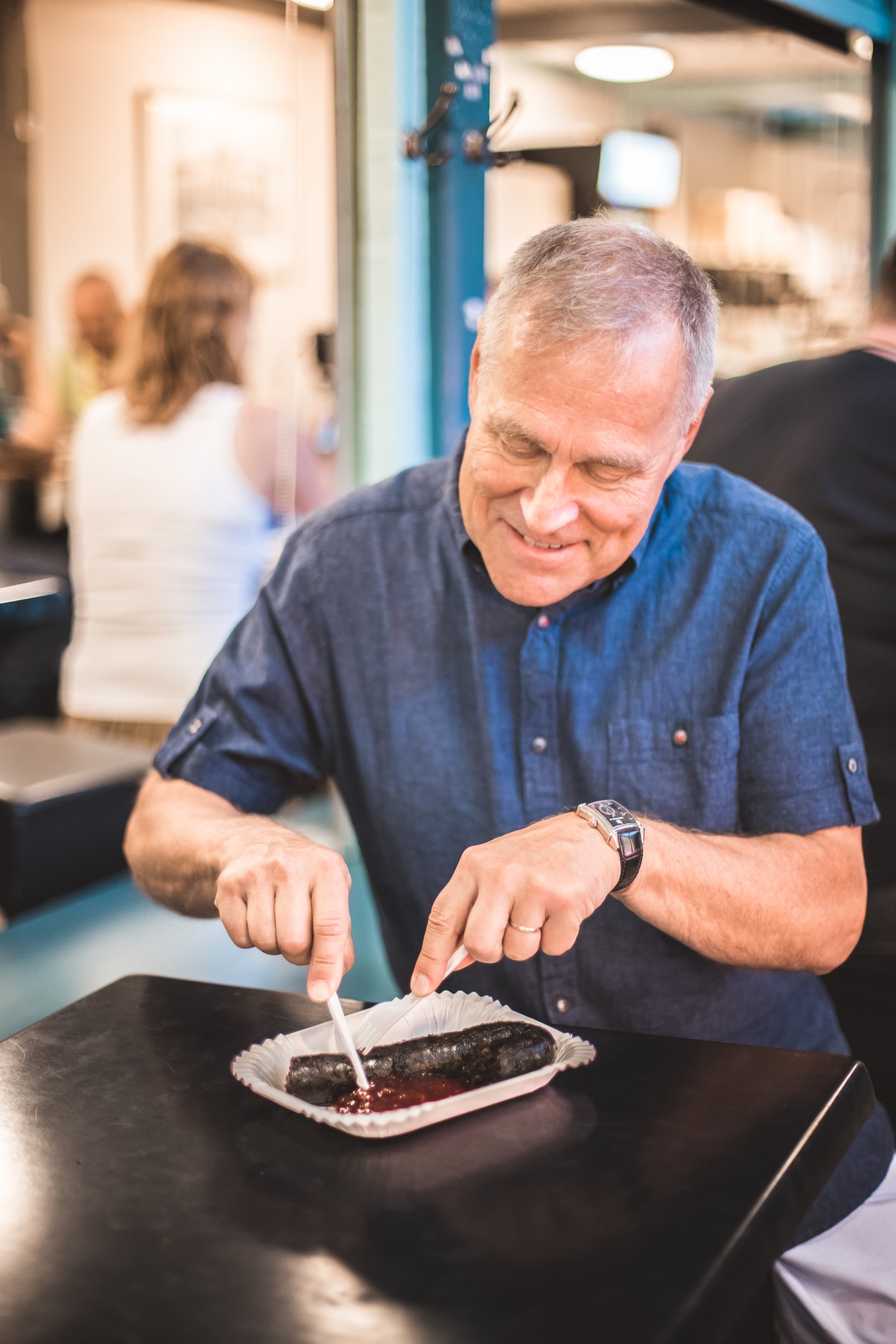 Man eating mustamakkara in Tampere Market Hall