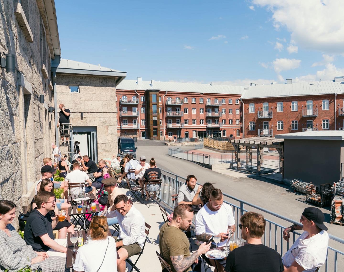 People enjoying a sunny day in a brewery's sun terrace in Turku, Finland
