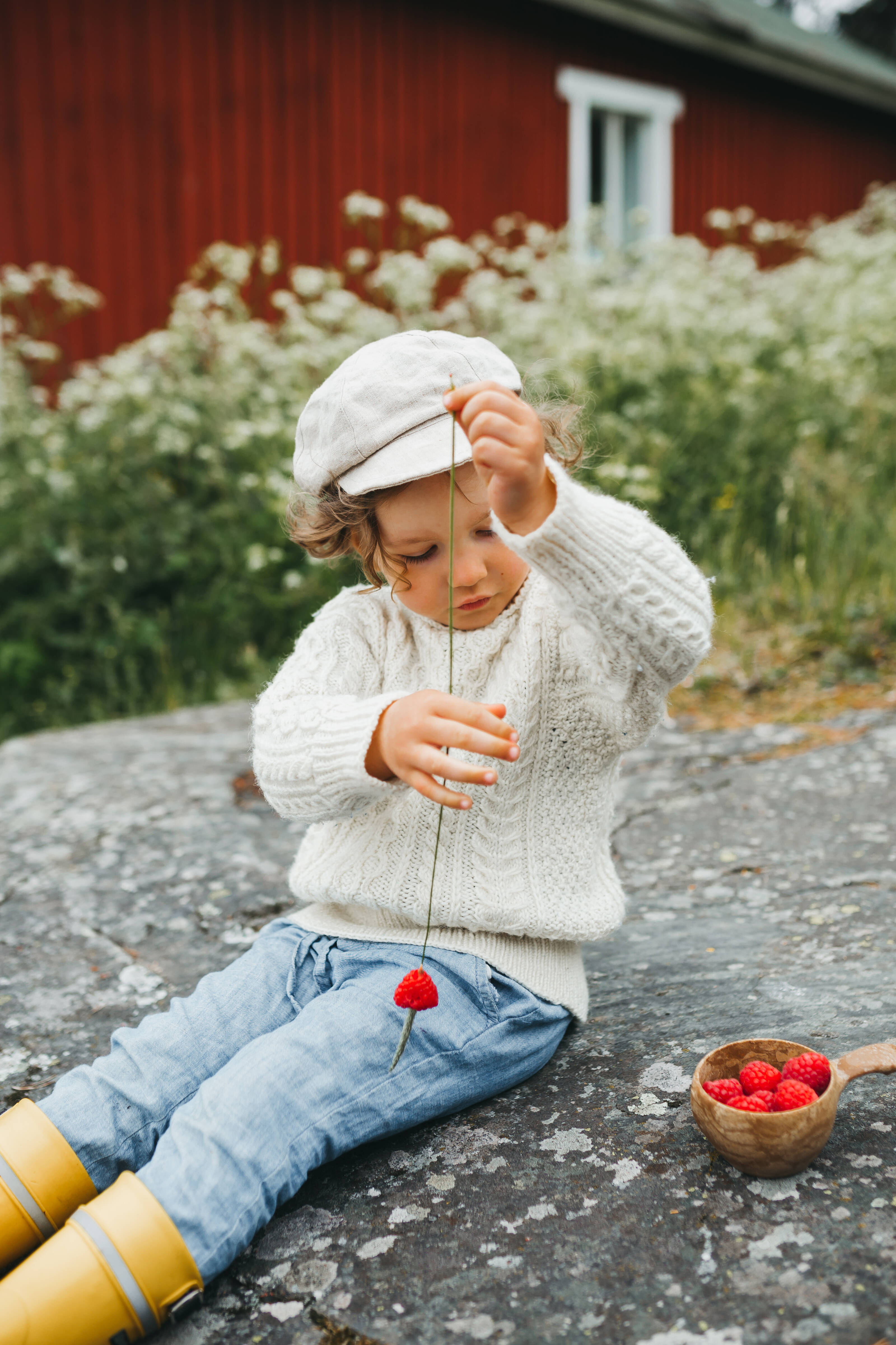 a child focussing on piercing berries through a haystack