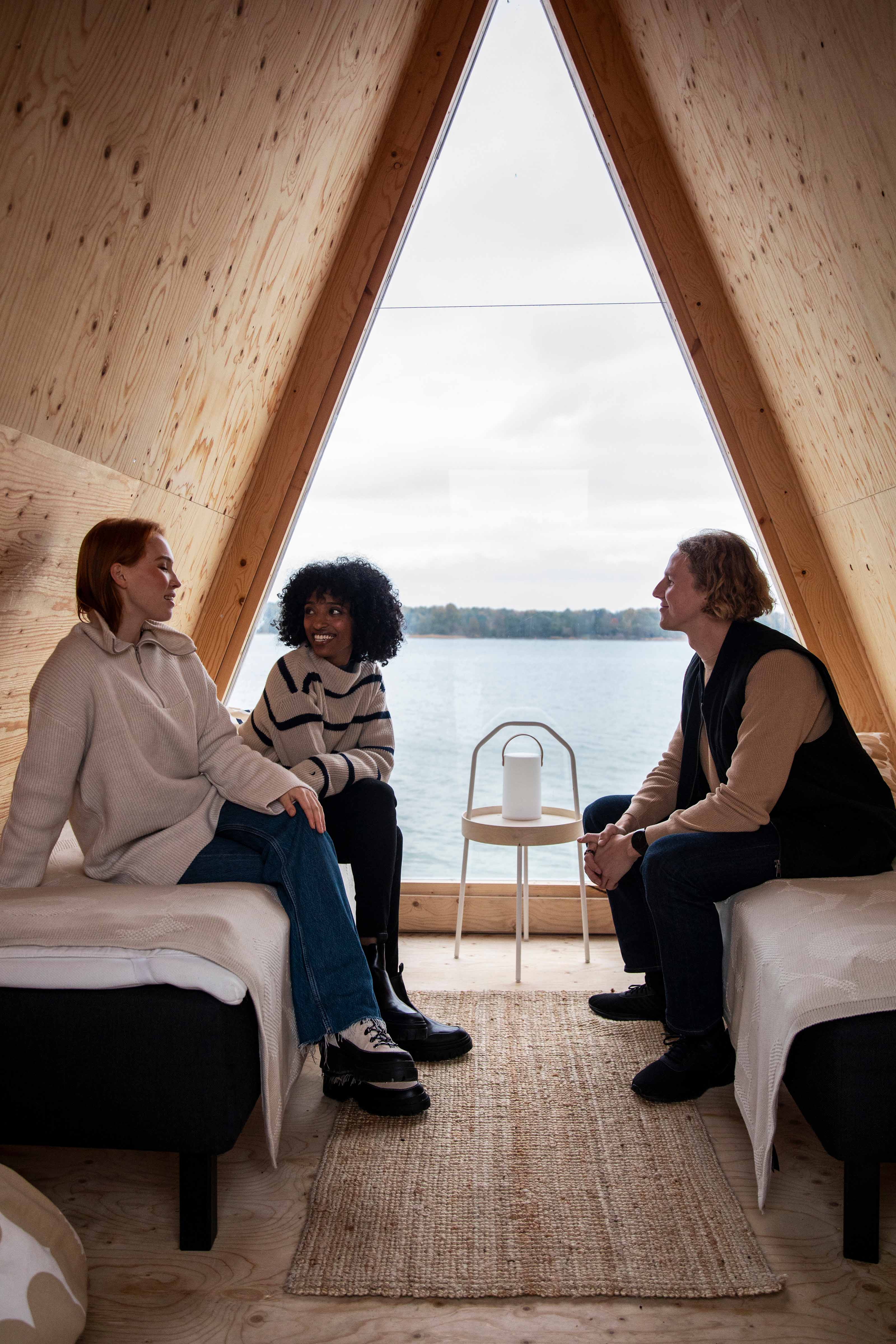 People sitting inside a carbon neutral minimalistic “Nolla” cabin with a seaview