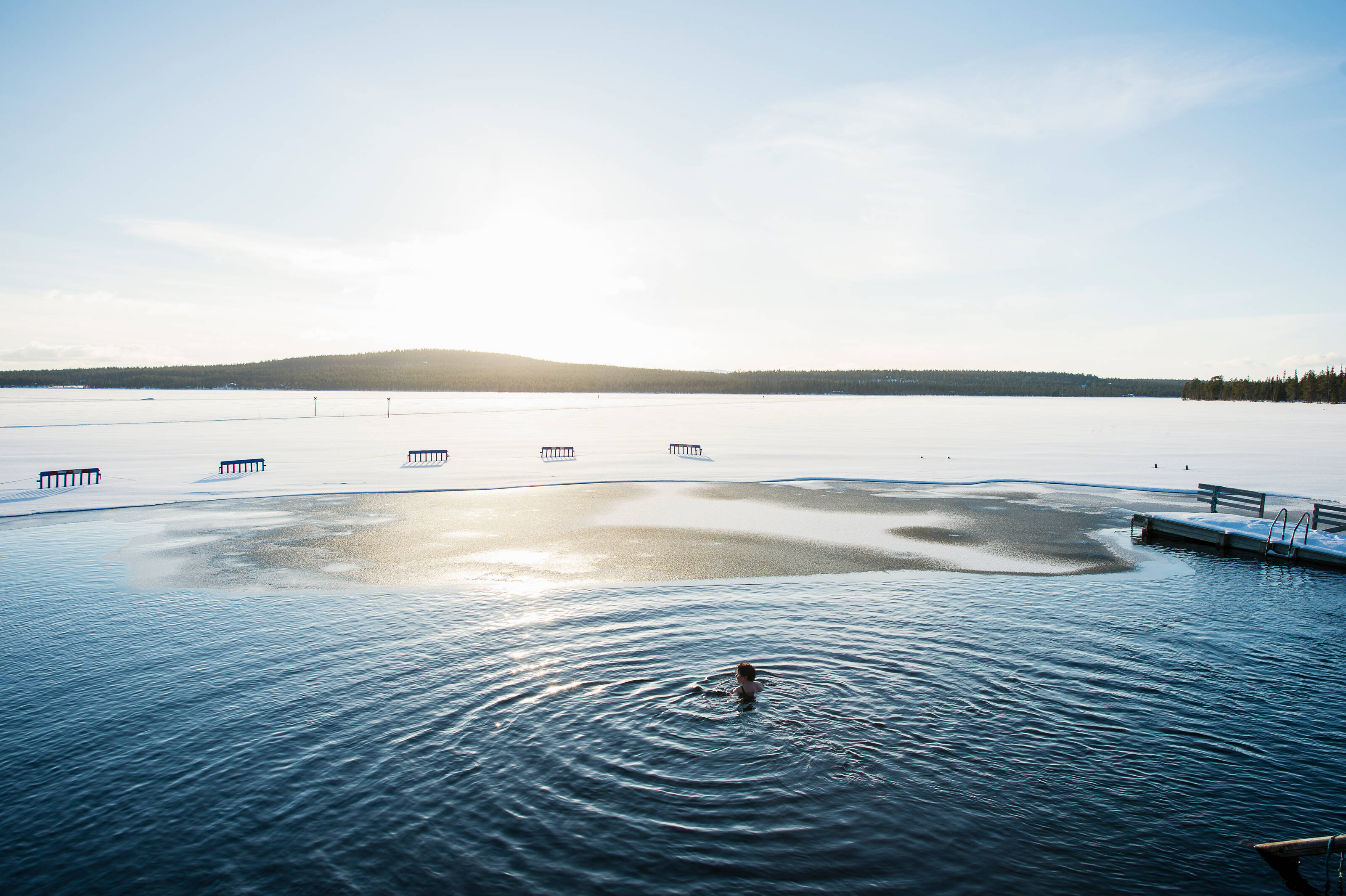 a woman ice swimming in the Finnish lakeland landscape